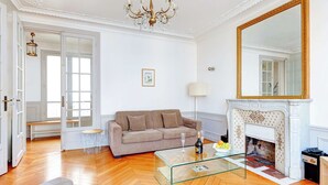 A living room with a sofa, glass coffee table, fireplace, and a large mirror.