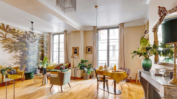 Ein geräumiges Wohnzimmer mit Holzboden, einem Essbereich mit gelbem Tisch und einem Kamin.