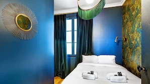 Ein Hotelzimmer mit einem großen Bett, einem runden Spiegel an der Wand und einer Tür mit grünem Vorhang.