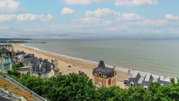 A coastal town with a beach, historic buildings, and a view of the sea.