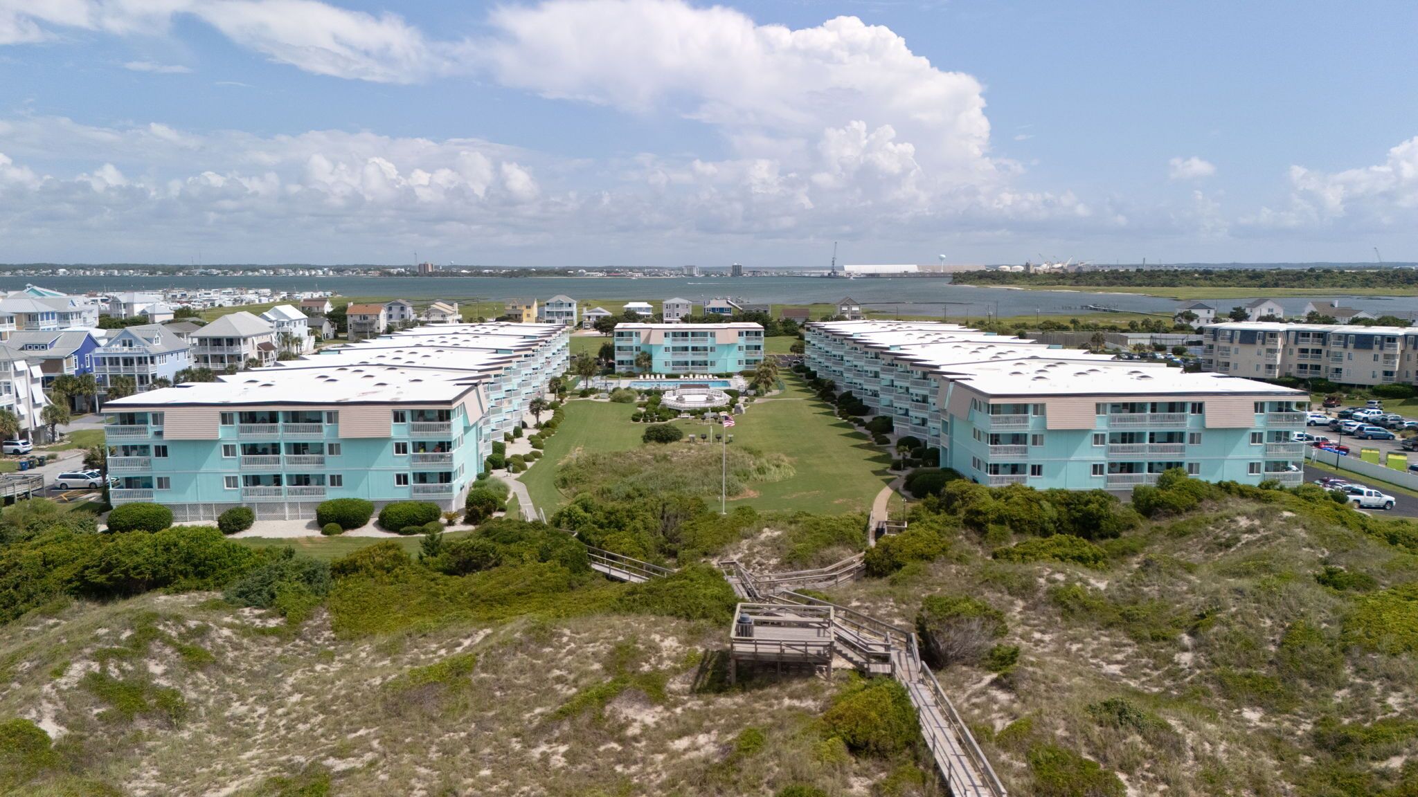 A coastal hotel with multiple-story buildings, a central courtyard, and a beach view.