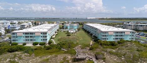 A coastal hotel with multiple-story buildings, a central courtyard, and a beach view.
