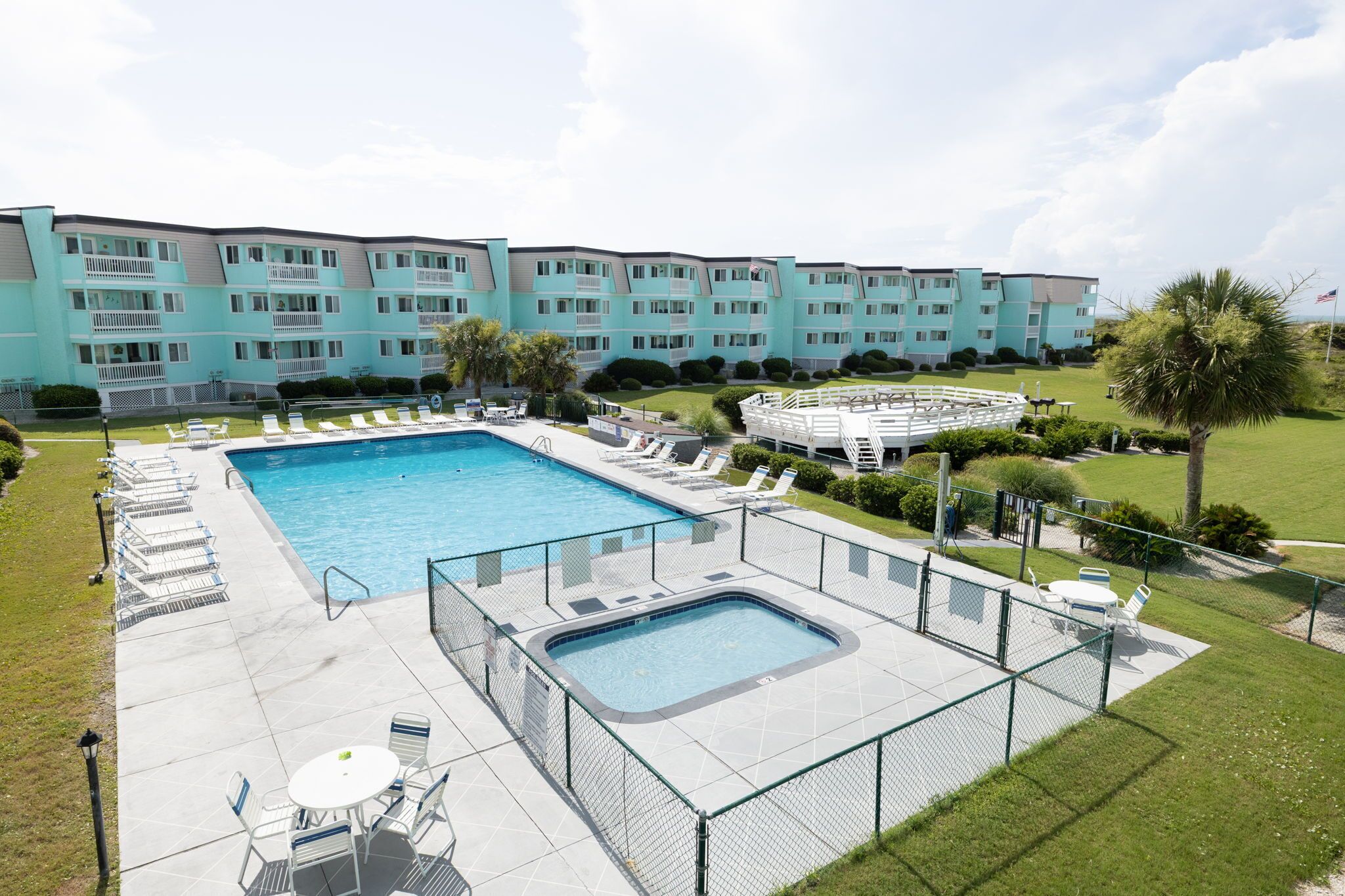 A hotel with a large swimming pool, outdoor seating, and a well-maintained lawn.