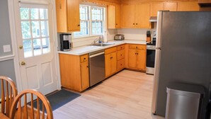 A kitchen with wooden cabinets, a stainless steel refrigerator, a dishwasher, and a window providing natural light. - 3 Bedroom home in West Harwich, sleeping 6 (West Harwich)