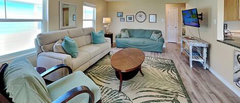 A living room with a ceiling fan, a sofa, a coffee table, and a television.
