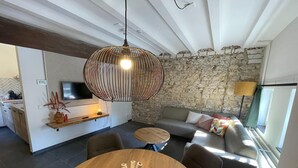 Ein modernes Wohnzimmer mit einer Steinwand, einem Holzespeisetisch mit Blumenarrangement, einer Couch mit Kissen und einer Hängelampe.