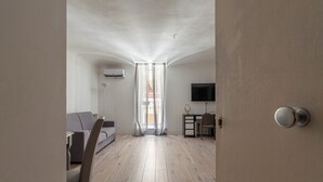 A modern living room with a sofa, a dining table, and a TV. - Real Umberto Apartments by Wonderful Italy (Palermo)