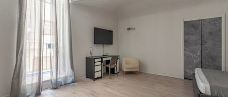 Une chambre à coucher comprenant un lit, un bureau, une chaise, une télévision et une armoire.