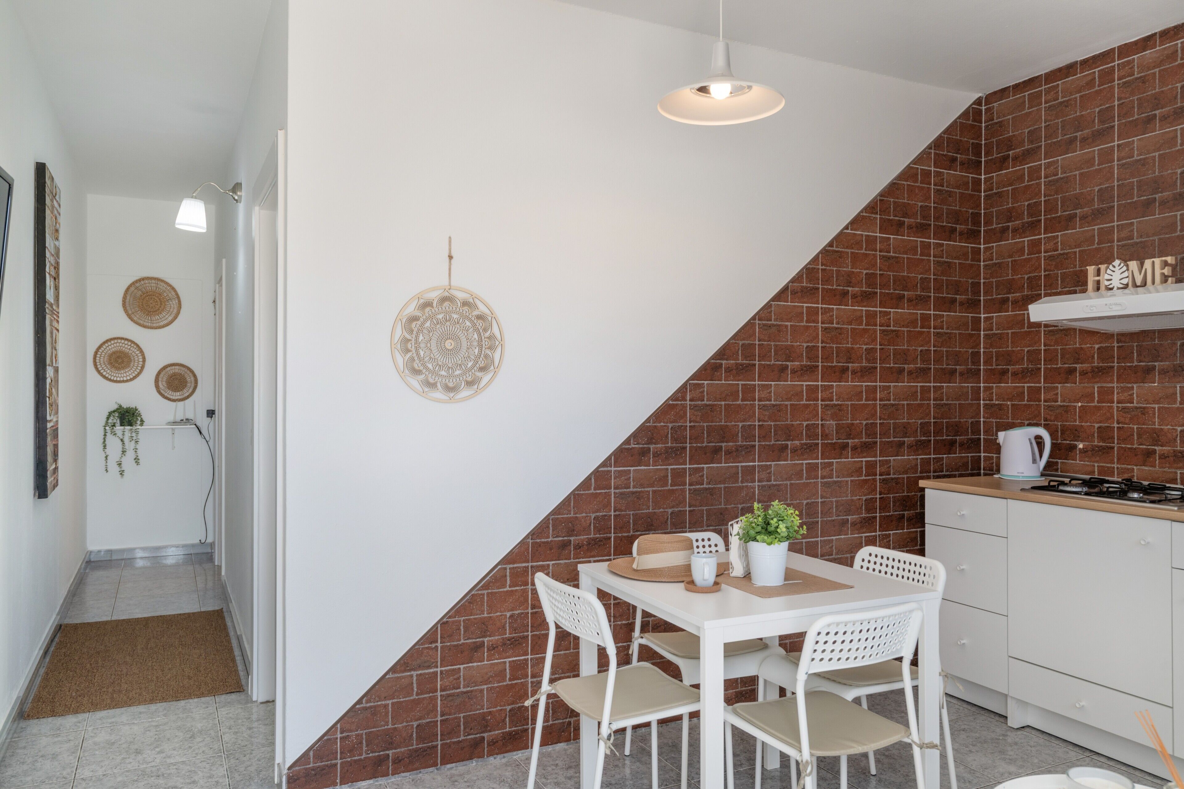 A kitchen with white cabinets, a stove, and a hanging light fixture.
