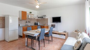 Una cocina compacta con comedor, un sofá y un televisor.