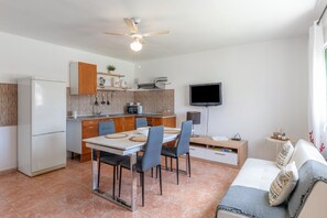 Una cocina compacta con comedor, un sofá y un televisor.