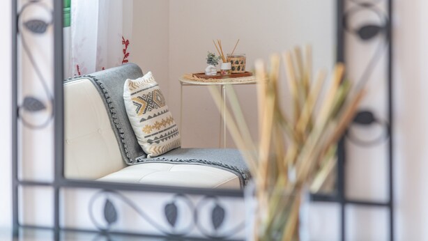 Una habitación con sofá, una mesita con un adorno y un jarrón con plantas secas.