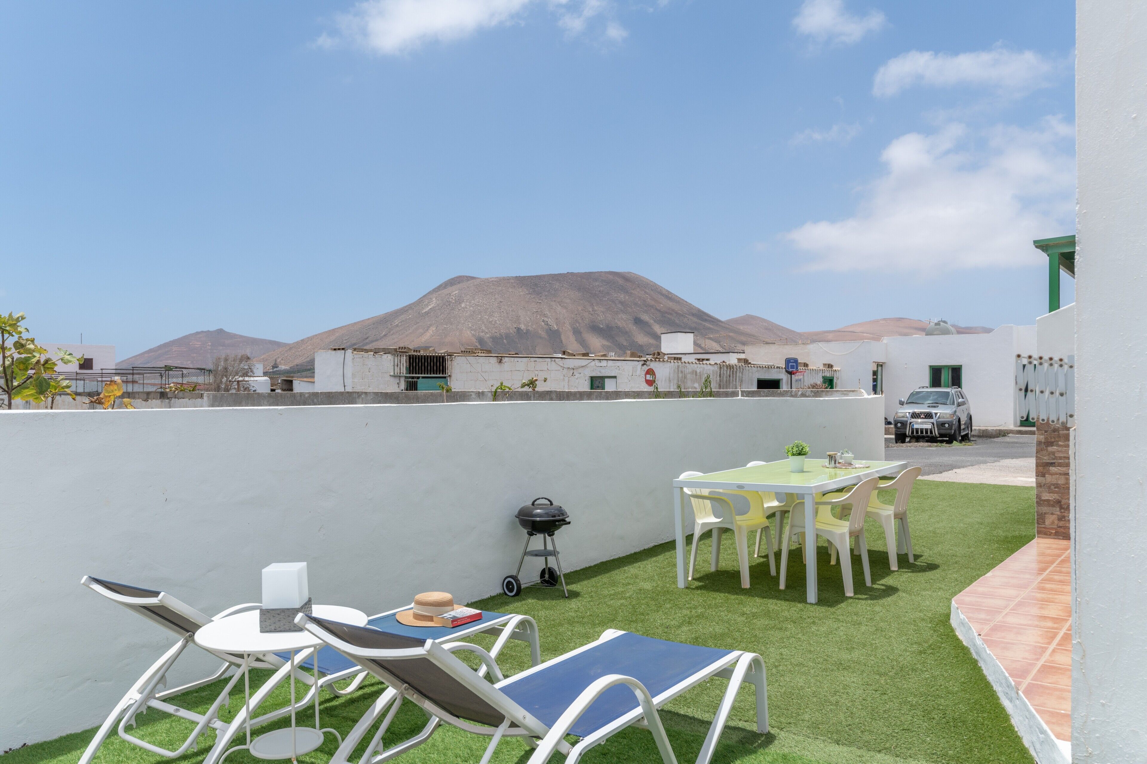 Una terraza en la azotea con vistas a montañas, una parrilla de barbacoa y mobiliario exterior.