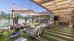 Un patio exterior con césped artificial, muebles de mimbre y una zona de bar.