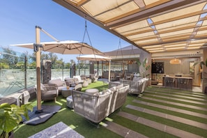 An outdoor patio with artificial grass, wicker furniture, and a bar area. - Maspalomas Villas by Dunas - Only Adults (San Bartolome de Tirajana)