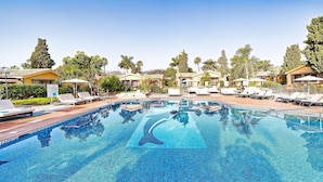 A swimming pool with lounge chairs and umbrellas, surrounded by palm trees and buildings. - Maspalomas Villas by Dunas - Only Adults (San Bartolome de Tirajana)