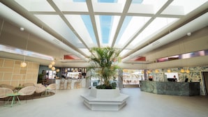 A spacious lobby with a central plant, seating areas, and a reception desk. - Maspalomas Villas by Dunas - Only Adults (San Bartolome de Tirajana)