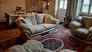 A cozy living room with a sofa, armchairs, a dining table, and a rug. - Charming cottage with all the comforts of home in Les Adjots (Les Adjots)