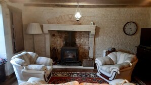 A cozy living room with a fireplace, two armchairs, a sofa, and a clock on the wall. - Charming cottage with all the comforts of home in Les Adjots (Les Adjots)