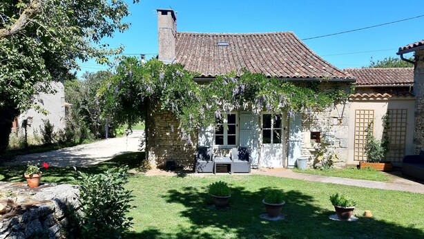 A stone house with a tiled roof, a small porch, and potted plants. - Charming cottage with all the comforts of home in Les Adjots (Les Adjots)