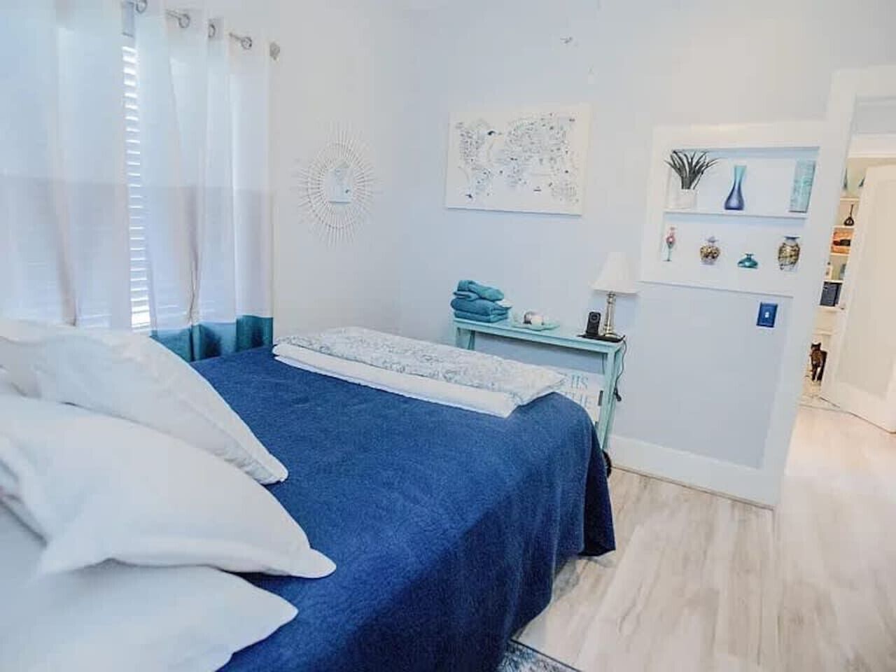 Un dormitorio con cama, escritorio y estante decorado con adornos.