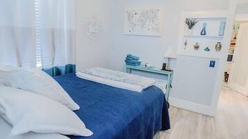 Un dormitorio con cama, escritorio y estante decorado con adornos.