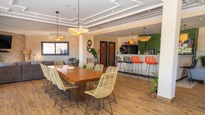 Ein geräumiger Wohnbereich mit einem Holzessttisch und Stühlen, einer Couch und einer Küchenzeile mit Bar.