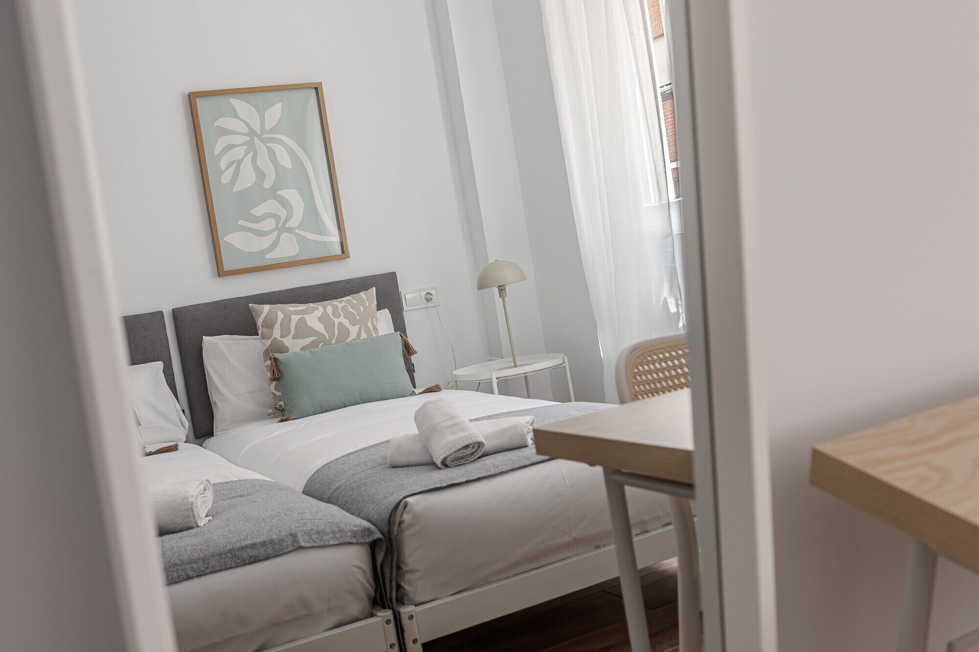 Een netjes ingerichte slaapkamer met een bed, nachtkastje, lamp en een lijstwerk aan de muur.