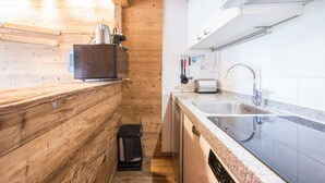 Een compacte keuken met houten wanden, een granieten aanrechtblad en moderne apparaten, zoals een broodrooster en vaatwasser.