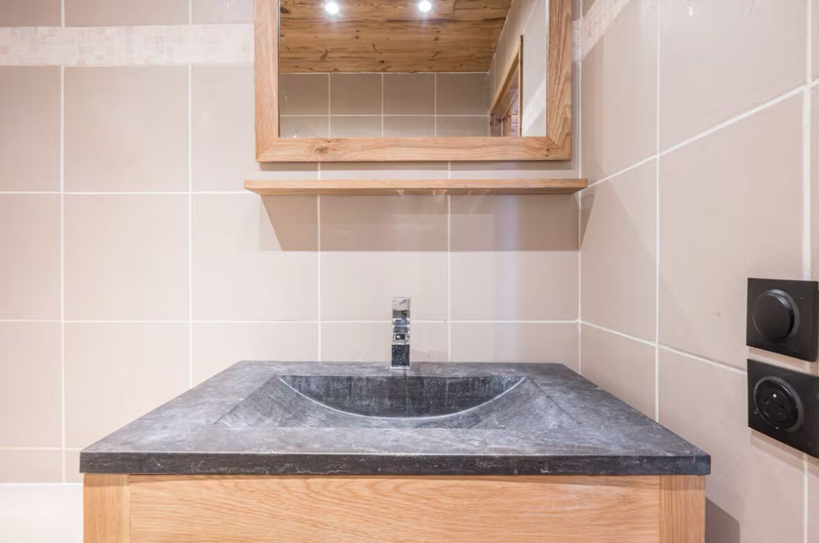 Une salle de bain avec un lavabo rectangulaire, un meuble-lavabo en bois et un miroir au-dessus du lavabo.