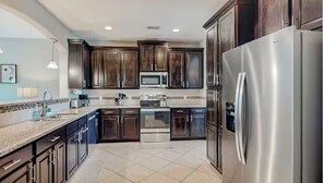 Una cocina moderna con alacenas de madera oscura, electrodomésticos de acero inoxidable y un salpicadero de azulejos.
