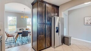 Una cocina moderna con un refrigerador de acero inoxidable integrado, armarios de madera oscura y un comedor con mesa y sillas.