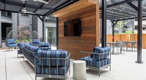 An outdoor seating area with cushioned chairs and a wooden wall.