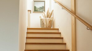 Een houten trap met een lichtgekleurde muur, een fotolijstje en een decoratieve mand.