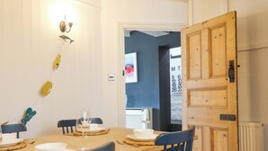 Een eetgedeelte met een houten tafel voor vier personen, stoelen en een wandlamp.