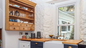 Een keuken met houten planken, een koffiezetapparaat, een waterkoker en een raam met uitzicht.