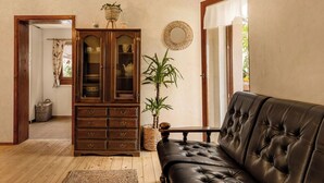 Una sala de estar con un sofá de cuero oscuro, un mueble de madera y una planta en maceta.