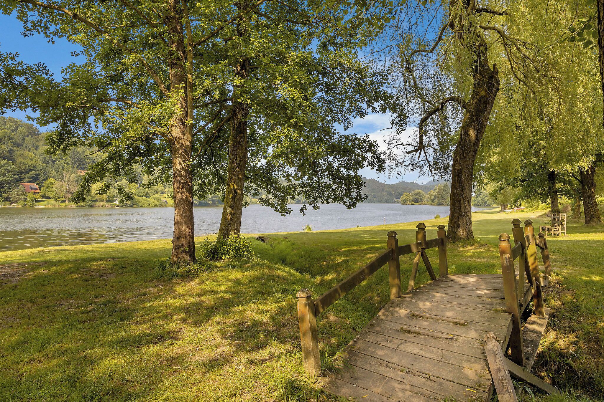 A wooden boardwalk leading to a lake surrounded by trees.