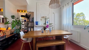 Un comedor moderno con una mesa de madera, sillas blancas y una lámpara colgante.