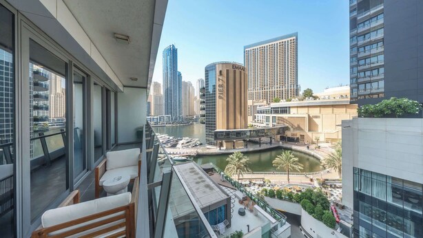 A balcony with a view of a marina, high-rise buildings, and a river. - StayShort - Spacious Marina Stay for 6 with Canal Views (Dubai Marina)
