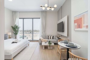 A modern hotel room with a large window, a sofa, a dining table, and a TV. - StayShort - Cozy & Spacious Studio in Town Square Sleeps 2 (Town Square)