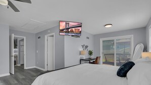 A modern hotel room with a large bed, a desk with a chair, a TV mounted on the wall, and a sliding glass door leading to a balcony. - Walk to Clark Lake + Beach Bar, Firepit, Porch, Sleeps 8 (Clarklake)