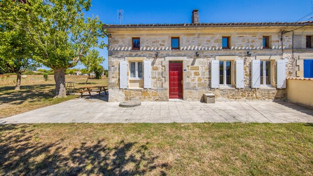 Un bâtiment en pierre avec une porte rouge, de nombreuses fenêtres et une cour dallée.