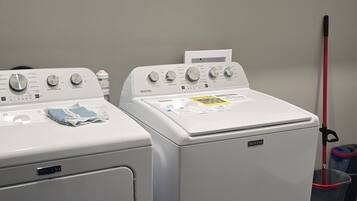 Dos lavadoras Maytag de carga frontal y un estante con productos de limpieza.