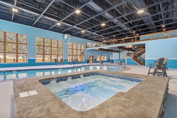 Piscina interna com hidromassagem, amplas janelas e um mezanino com assentos.