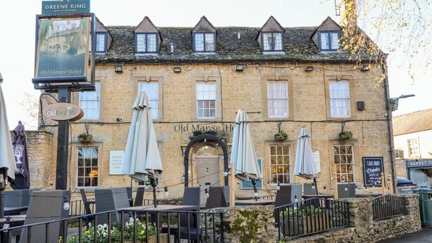 A traditional stone building with a sign for 'Old Manse Hotel' and 'Greene King'. - Lorien (Cheltenham)