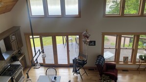 A spacious living area with large windows, a kitchen with a gas stove, and a deck with outdoor furniture.