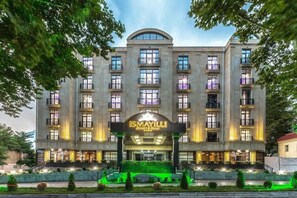 Un hôtel à plusieurs étages, doté d’une entrée imposante, de balcons et d’un jardin paysager à l’avant.