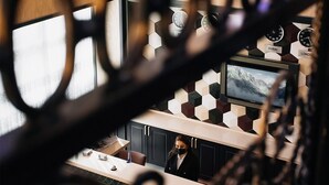 Zona de recepción de un hotel con una recepcionista, un mostrador y relojes que muestran la hora de Dubái y Londres.