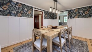 A dining room with a wooden table, white paneling, and a floral-patterned wallpaper. - Highville Hideaway - 2 bed, 1 bath, country views (Conestoga)